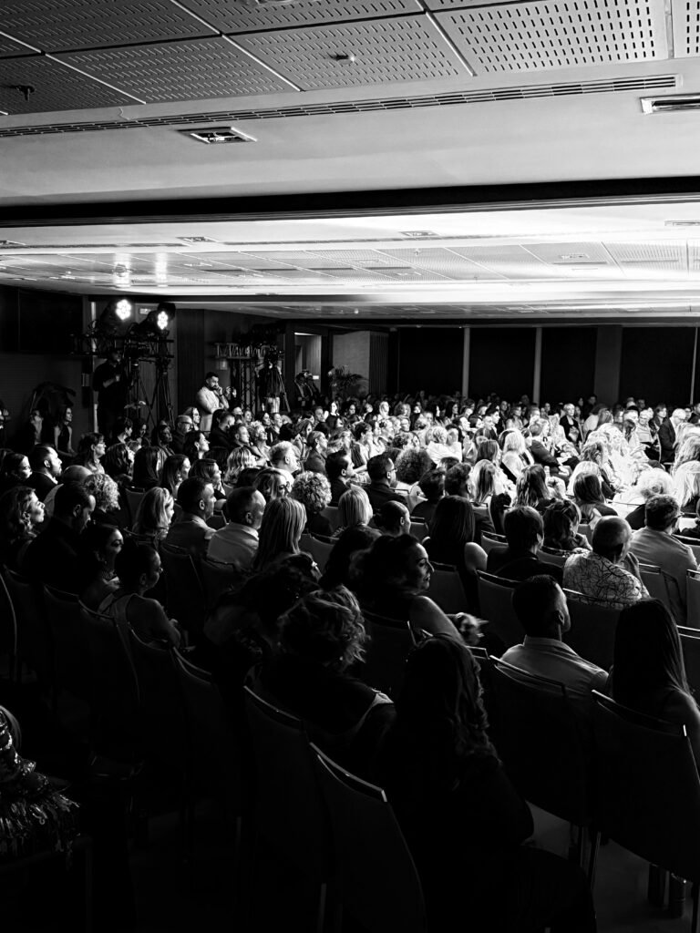 Professional hairstylists attending a live hair education masterclass seminar with stage lighting and expert demonstration at Hair Mastery event